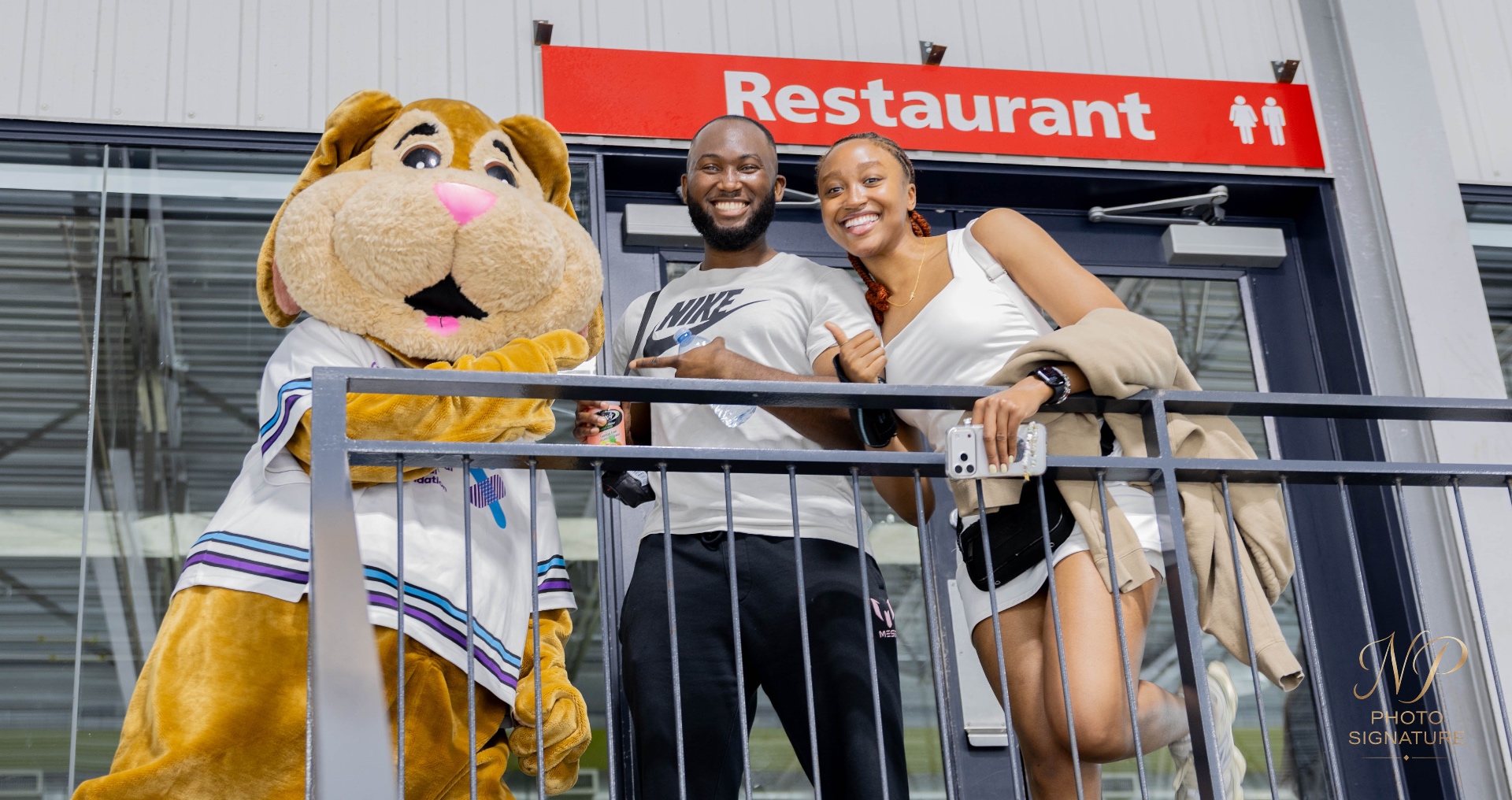 Visiteurs souriants avec la mascotte